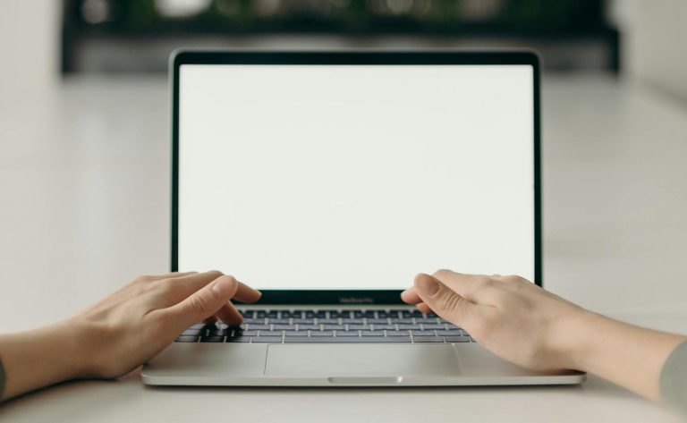 A minimalist workspace featuring an open laptop in a bright, serene indoor setting.