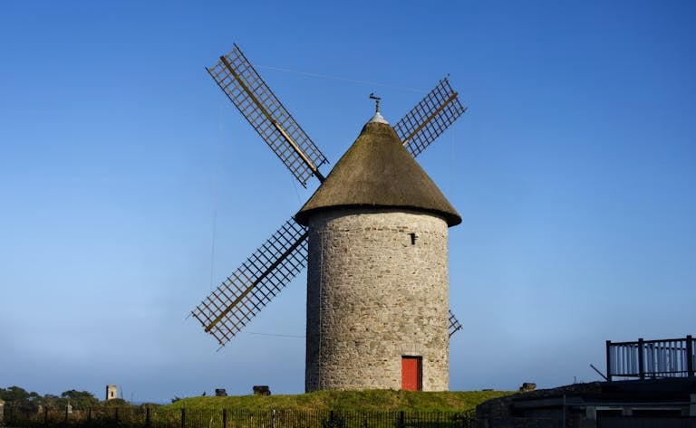 A traditional windmill tower in Skerries, Ireland, under a clear blue sky.