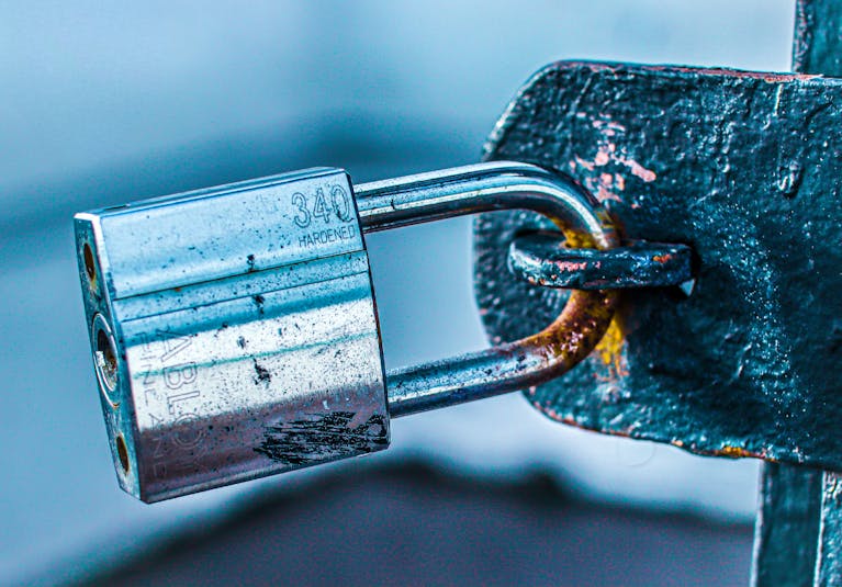 Detailed close-up of a durable padlock securing a rusted metal gate, emphasizing safety and protection.
