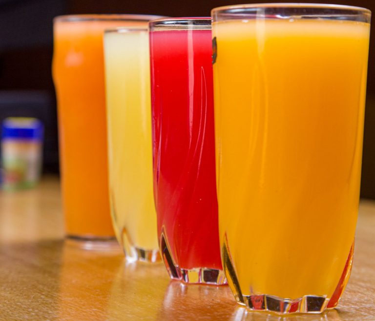 Colorful assortment of fruit juices in glasses on a wooden table, ideal for beverage and lifestyle themes.