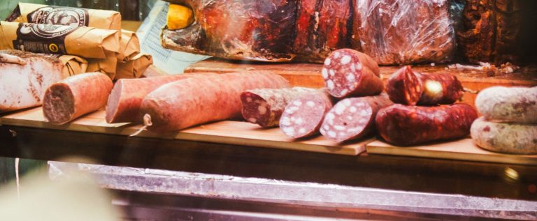A detailed view of various meats displayed in a traditional Roman deli, showcasing salami and cured meats.